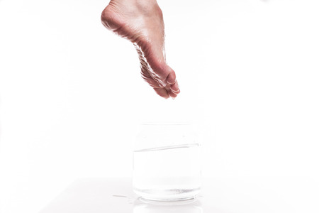 foot girl with a dry and rough skin and calluses on the heel moistened with water from the jar.の写真素材