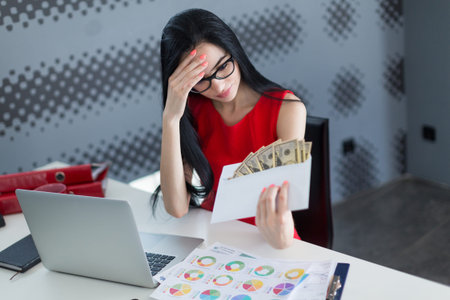 Young business woman holding money in envelope in the office
