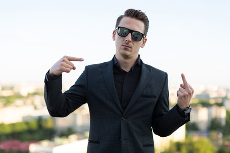 young guy in a suit and wearing glasses on the background of the city