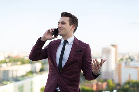 young man talking on the phone on the background of the cityの写真素材