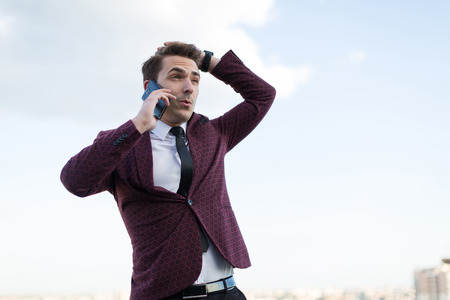 young man talking on the phone on the background of the cityの写真素材