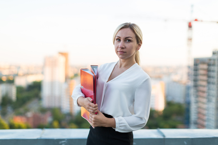 Girl with a folder on the background of the cityの写真素材