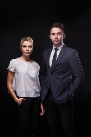 stylish, trendy and modern business man and woman on black background looking confidently at the camera.の写真素材