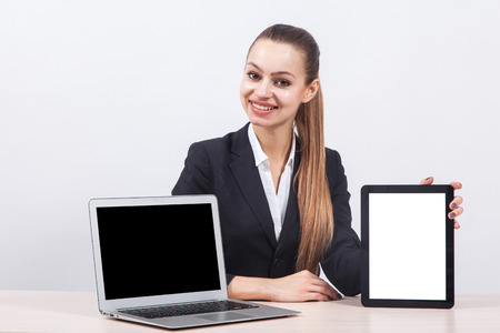 Business woman sitting at the table and keeps ahead screen laptop and the tablet display detailed forwardの写真素材