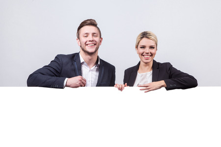 studio portrait on white background of successful business men and women in business suits next to the board for advertising which could be your textの写真素材