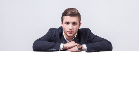 studio portrait on white background successful businessman in a business suit with a board for a number of advertising which could be your text.の写真素材