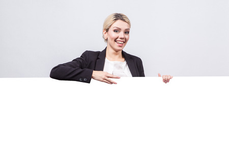studio portrait on white background successful business woman in a business suit with a board for a number of advertising which could be your text.の写真素材