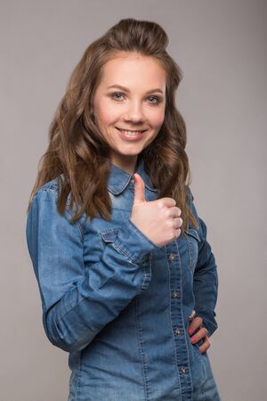 portrait energetic cheerful student girl on gray background in a denim shirt with a broad smile on his face and bright emotionsの写真素材