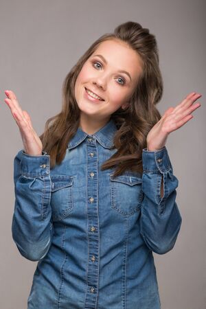 portrait energetic cheerful student girl on gray background in a denim shirt with a broad smile on his face and bright emotionsの写真素材