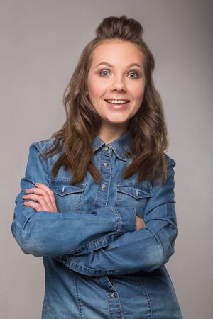 portrait energetic cheerful student girl on gray background in a denim shirt with a broad smile on his face and bright emotionsの写真素材