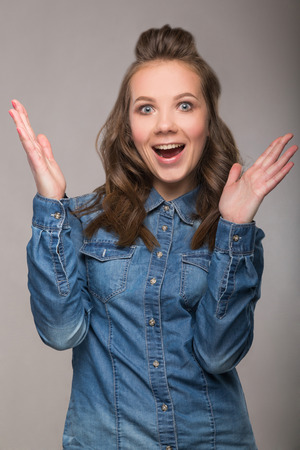 portrait energetic cheerful student girl on gray background in a denim shirt with a broad smile on his face and bright emotionsの写真素材