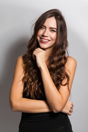 young beautiful stylish girl in a black business dress and sunglasses standing on a white background with a snow-white smile, smiling, picture with depth of field,の写真素材