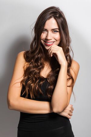 young beautiful stylish girl in a black business dress and sunglasses standing on a white background with a snow-white smile, smiling, picture with depth of fieldの写真素材