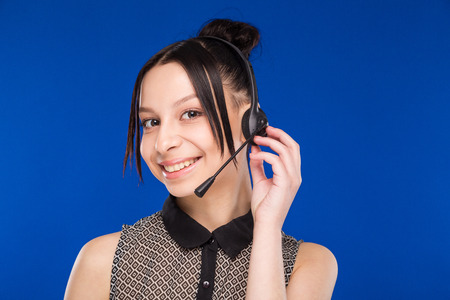 young girl with a headset in white clothes on a blue backgroundの写真素材