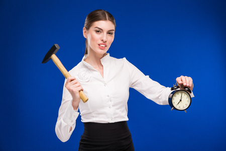 woman with hammer and alarm clock in hands on a blue backgroundの写真素材