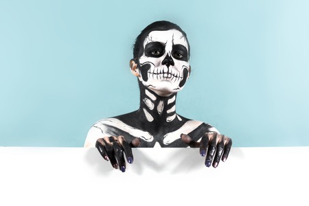 Isolated on blue, closeup picture, young brunette caucasian attractive woman with scull body art holds megaphone, grey eyes, languid lookの写真素材