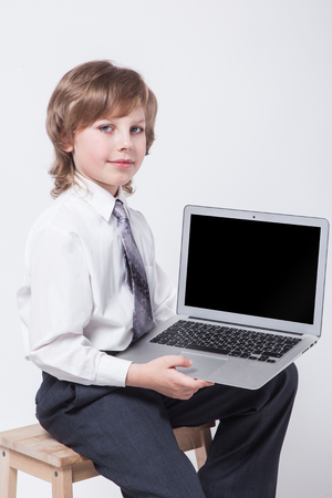 an ambitious young man in shirt and tie sitting with a laptop and looking at the cameraの写真素材