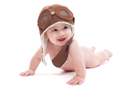 cute smiling baby in the cap of the pilot is flying on a white background. Photo with artistic blur and depth of fieldの写真素材