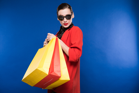 young girl in glasses with packages on a blue backgroundの写真素材