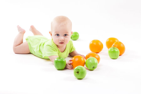 baby lying on the background and smiling among fruits. Photo with depth of fieldの写真素材