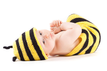 isolated on white, cute serious caucasian baby boy in diaper and bee costume lies on sideの写真素材