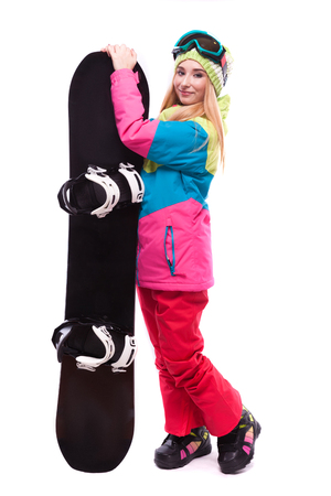 attractive young caucasian girl in colorful ski suit, red trousers and blue ski glasses, hold black snowboard, turned girlの写真素材