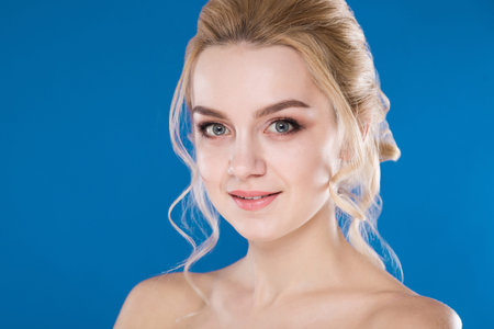 portrait of the blonde with bared shoulders against a blue backgroundの写真素材