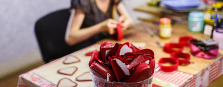 woman manufacturing heart-shaped red purses. purses are in focus. blurred background.の写真素材