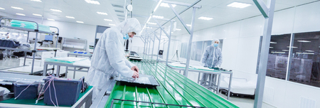 factory workers in white lab suits and face masks, producing tv sets on a green assebly line with some modern equipmentの写真素材