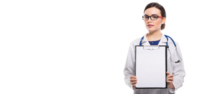 Portrait of young attractive female doctor in white coat standing in office smiling looking in camera and showing clipboard to patient confident friendly experienced skilful positive cheerful successful brunette caucasian beautiful pretty gp copyspace.の写真素材