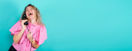 Portrait of attractive laughing curly-haired woman in pink blouse isolated on blue background...
