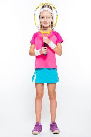 Adorable smiling little girl in sportswear holding tennis racket with her hands on white background brunette caucasian beautiful funny attractive friendly isolatedの写真素材