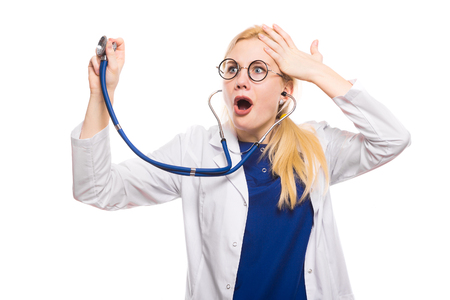 Portrait of shocked female doctor in white coat and glasses with stethoscope listening and hold hand on her head isolated on white background with copyspace.の写真素材