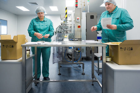 Pharmaceutical technicians work in sterile working conditions at pharmaceutical factory. Scientists...