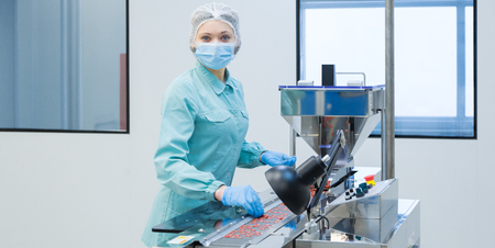 Pharmaceutical technician in sterile environment working on production of pills at pharmacy factoryの写真素材