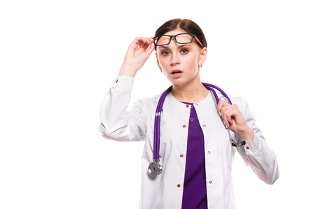 Portrait of young attractive serious woman doctor standing in office waiting for patient looking in camera in white uniform caucasian brunette puzzled confused astonishedの写真素材