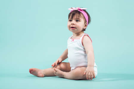 Adorable funny sweet little girl in white dress isolated on blue looking awayの写真素材
