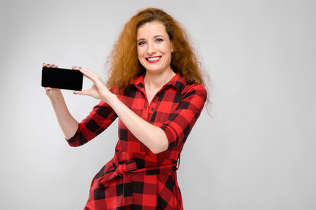 Attractive caucasian young girl with red lips and curly hair looking in camera with smile successful...