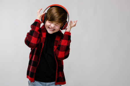 Portrait of small adorable thinking stylish confident caucasian guy standing in studio looking in camera with closed eyes annoyed irritatedの写真素材