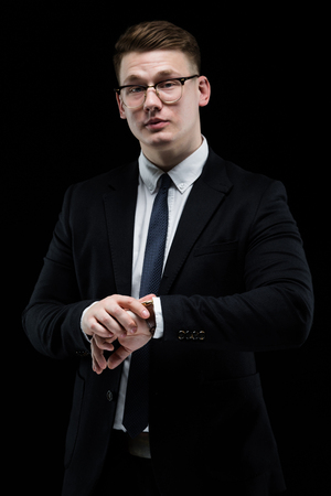 Young caucasian elegant successful smiling smart business man in black suit and tie standing in office looking in cameraの写真素材