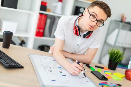 A young man in a white shirt and light jeans is working in a bright office. photo with depth of...