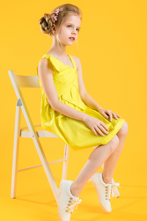 Portrait of a teenage girl in a yellow dress. At the child hair are collected in a fascicle and are fastened by a beautiful hairpin.の写真素材