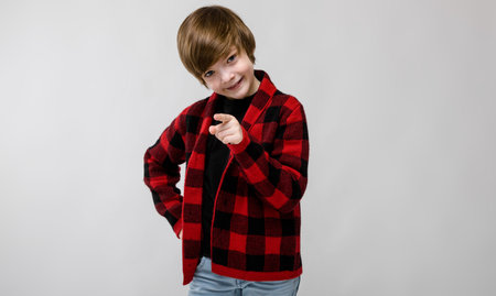 Portrait of small adorable thoughtful stylish sad upset confident caucasian guy standing in studio looking in camera showing on cameraの写真素材