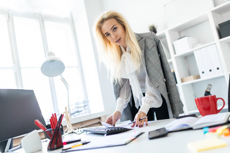 A slender young girl in a white blouse, gray jacket and dark trousers is working in the office. The girl has white long hair. photo with depth of field.の写真素材