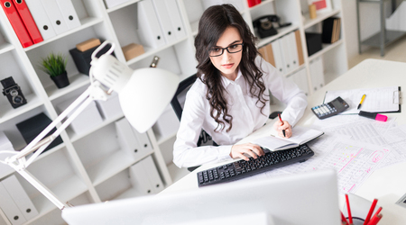 A charming young girl is working in a bright office. photo with depth of field.の写真素材