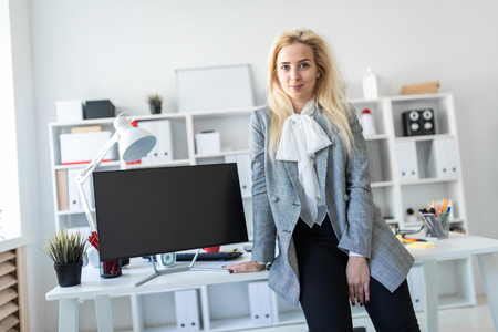 A slender young girl in a white blouse, gray jacket and dark trousers is working in the office. The girl has white long hair. photo with depth of field.の写真素材