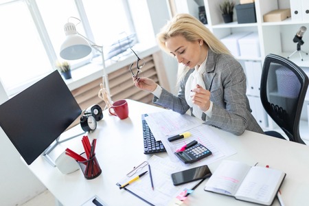 A slender young girl in a white blouse, gray jacket and dark trousers is working in the office. The girl has white long hair. photo with depth of field.の写真素材
