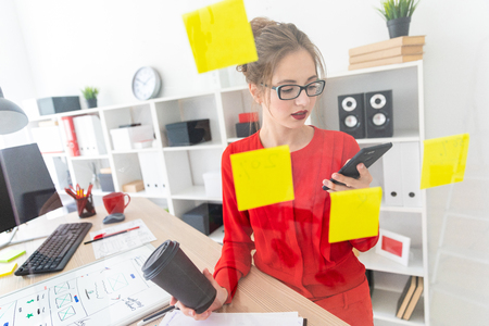 Beautiful young girl in glasses and a red shirt is working in the office. photo with depth of field.の写真素材