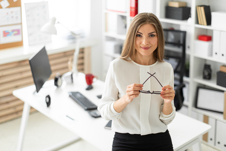 Beautiful young blonde girl in white blouse and black skirt is working in the office. photo with depth of fieldの写真素材