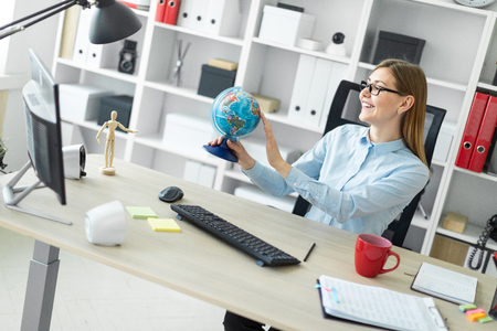 A beautiful red-haired young girl in a white T-shirt and a yellow jacket is working in a bright office. photo with depth of fieldの写真素材